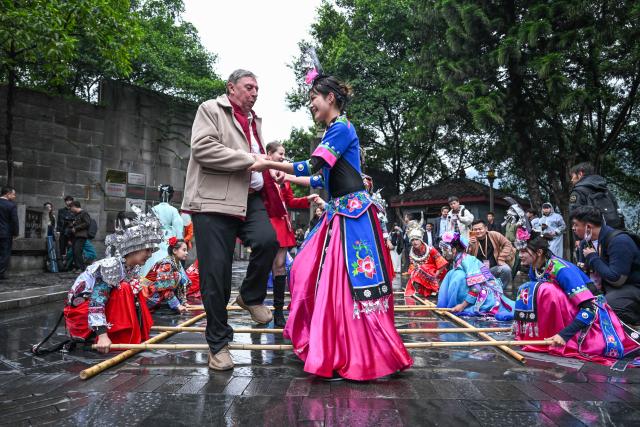 (251104) -- GUIYANG, Nov. 4, 2025 (Xinhua) -- Foreign guests tries ethnic dances with local performers in Maotai Town, Renhuai City, southwest China's Guizhou Province, Oct. 29, 2025. TO GO WITH "China Focus: China's traditional liquor brewing industry embraces digital transformation" (Xinhua/Yang Wenbin)