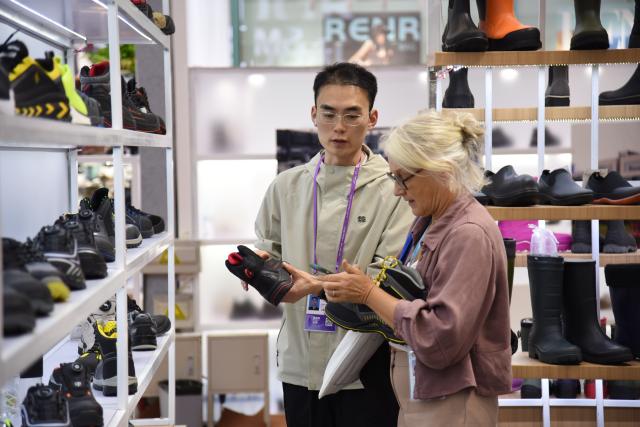 (251104) -- GUANGZHOU, Nov. 4, 2025 (Xinhua) -- A buyer (R) learns about shoes during the 138th edition of the China Import and Export Fair in Guangzhou, south China's Guangdong Province, Nov. 4, 2025. The 138th Canton Fair, known officially as the China Import and Export Fair, came to a close on Tuesday in Guangzhou, the capital city of south China's Guangdong Province, having seen a record number of overseas buyers attend. (Xinhua/Hong Zehua)