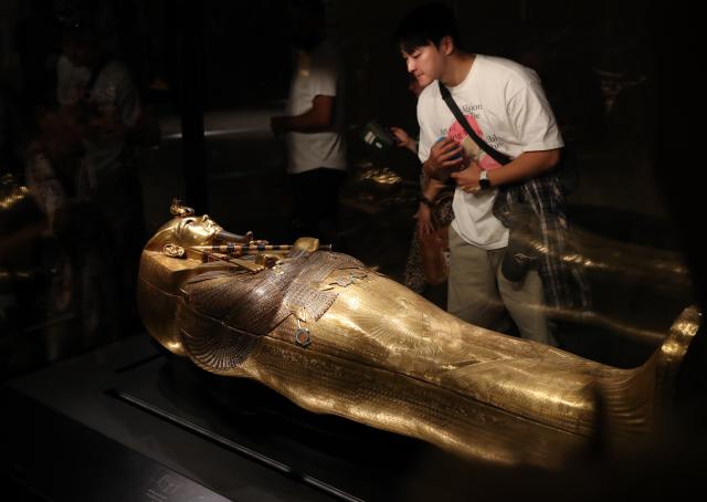 (251104) -- CAIRO, Nov. 4, 2025 (Xinhua) -- Tourists view a gilded coffin at the King Tutankhamun exhibition hall of the Grand Egyptian Museum in Giza, Egypt, on Nov. 4, 2025. The Grand Egyptian Museum (GEM) , the world's largest museum dedicated to a single civilization, opened to the public on Tuesday. (Xinhua/Sui Xiankai)