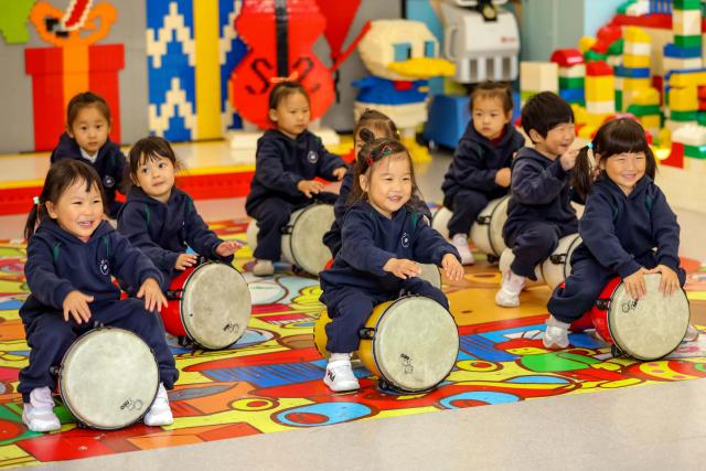 (251107) -- SHANDONG, Nov. 7, 2025 (Xinhua) -- Children learn to play African drums at a nursery center in Qingdao City, east China's Shandong Province, Nov. 4, 2025. Shandong Province has rolled out a series of policies such as developing childcare institutions, increasing kindergarten nursery classes, and offering childcare service in communities to promote its inclusive childcare system, with a focus on the caring of children under three years old. (Photo by Zhang Ying/Xinhua)