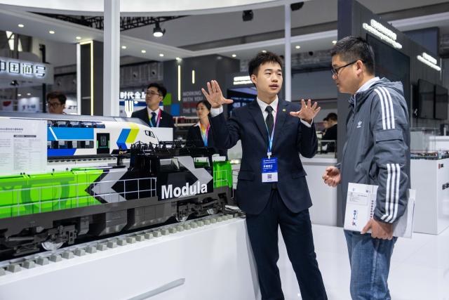 (251107) -- ZHUZHOU, Nov. 7, 2025 (Xinhua) -- An exhibitor introduces to a visitor a hybrid-power locomotive during the 2025 China International Rail Transit & Equipment Manufacturing Industry Exposition in Zhuzhou, central China's Hunan Province, Nov. 7, 2025. Boasting an exhibition area of about 40,000 square meters, the expo kicked off here on Friday, covering a wide range of fields such as rail transit and equipment manufacturing, key parts and raw materials, high-tech demonstration, intelligent systems, operation and maintaining, and infrastructure design and consultation. Magnetic levitation and other cutting-edge technologies are highlighted at this event. (Xinhua/Chen Sihan)