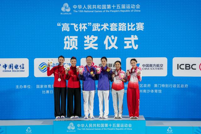 (251107) -- GUANGZHOU, Nov. 7, 2025 (Xinhua) -- Gold medalist Tong Xin (3rd R) of Fujian, silver medalist Wu Xu (2nd L) of Hebei and bronze medalist Liang Biying (1st R) of Guangdong pose for photos with their coaches during the awarding ceremony for the women's Taijiquan-Taijijian of Wushu Taolu event at China's 15th National Games in Guangzhou, south China's Guangdong Province, Nov. 7, 2025. (Xinhua/Jigme Dorji)