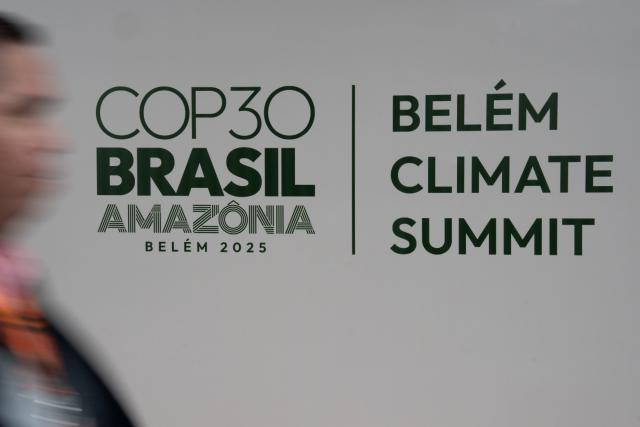 (251107) -- BELEM(BRAZIL), Nov. 7, 2025 (Xinhua) -- A man walks past the logo of the 30th Conference of the Parties (COP30) of the United Nations Framework Convention on Climate Change and the Belem Climate Summit in Belem, Brazil, Nov. 6, 2025. UN Secretary-General Antonio Guterres and world leaders on Thursday urged governments to take immediate, decisive actions and make concerted efforts to combat climate change. (Photo by Lucio Tavora/Xinhua)