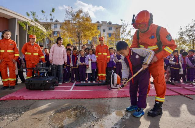 (251108) -- YINCHUAN, Nov. 8, 2025 (Xinhua) -- A staff member of Ningxia Helan Mountain National Nature Reserve Administration instructs a student to use equipment for forest fire prevention at a primary school in Yinchuan, northwest China's Ningxia Hui Autonomous Region, Nov. 7, 2025. Currently, the risk of forest fire is high across the Helan Mountain. Staff members of local nature reserve administration have rolled out a series of educational activities with the theme of forest fire prevention, aiming to enhance students' safety awareness via lectures, equipment demonstrations, and hands-on experiences. (Xinhua/Yang Zhisen)