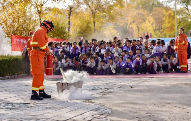 (251108) -- YINCHUAN, Nov. 8, 2025 (Xinhua) -- A staff member of Ningxia Helan Mountain National Nature Reserve Administration demonstrates the use of fire extinguisher to students at a primary school in Yinchuan, northwest China's Ningxia Hui Autonomous Region, Nov. 7, 2025. Currently, the risk of forest fire is high across the Helan Mountain. Staff members of local nature reserve administration have rolled out a series of educational activities with the theme of forest fire prevention, aiming to enhance students' safety awareness via lectures, equipment demonstrations, and hands-on experiences. (Xinhua/Yang Zhisen)