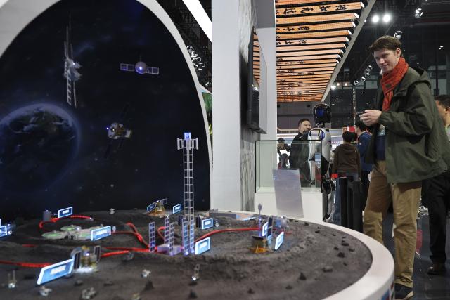 (251108) -- SHANGHAI, Nov. 8, 2025 (Xinhua) -- A guest views a model displaying China's lunar exploration program at the China Pavilion during the eighth China International Import Expo (CIIE) in east China's Shanghai, Nov. 8, 2025. Over 30 foreign talents and their families were invited to visit the eighth CIIE at the National Convention and Exhibition Center (Shanghai) during a themed event on Saturday. (Xinhua/Fang Zhe)