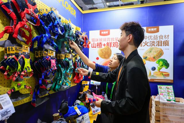 (251108) -- SHANGHAI, Nov. 8, 2025 (Xinhua) -- A customer (R) selects products at a pet supplies store at the Consumer Goods Exhibition area during the eighth China International Import Expo (CIIE) in east China's Shanghai, Nov. 8, 2025. At the Consumer Goods Exhibition area of the eighth CIIE, apparel, daily chemicals, home furnishings, and cultural and sports products were prominently showcased, reflecting global consumption trends and improvements in quality of life. (Xinhua/Liu Jiaqi)