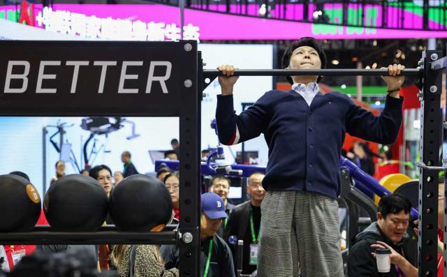 (251108) -- SHANGHAI, Nov. 8, 2025 (Xinhua) -- A man participates in the bodyweight pull-up challenge at the booth of Johnson Health Tech at the Consumer Goods Exhibition area during the eighth China International Import Expo (CIIE) in east China's Shanghai, Nov. 8, 2025. At the Consumer Goods Exhibition area of the eighth CIIE, apparel, daily chemicals, home furnishings, and cultural and sports products were prominently showcased, reflecting global consumption trends and improvements in quality of life. (Xinhua/Wang Zecong)