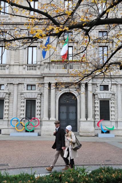 (251109) -- MILAN, Nov. 9, 2025 (Xinhua) -- People walk past the emblems of Olympic and Paralympic Games in front of the City Hall of Milan in Milan, Italy, Oct. 29, 2025. The Milan-Cortina 2026 Olympic Winter Games will open on February 6, 2026 at Milan's San Siro Stadium. (Xinhua/Li Jing)