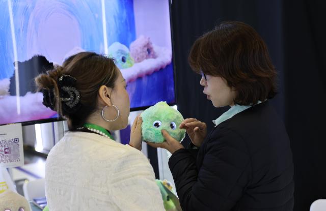 (251109) -- SHANGHAI, Nov. 9, 2025 (Xinhua) -- A staff member (R) introduces an AI-powered emotional healing robot at the Innovation Incubation Special Section during the eighth China International Import Expo (CIIE) in east China's Shanghai, Nov. 9, 2025. The Innovation Incubation Special Section at this year's CIIE provides participating global startups and talents with technological innovation resources and cooperation opportunities to jointly explore and develop the Chinese market. (Xinhua/Fang Zhe)