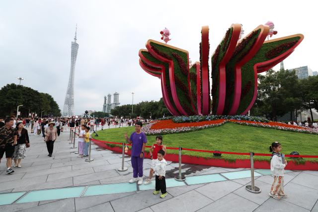 (251109) -- GUANGZHOU, Nov. 9, 2025 (Xinhua) -- People pose for photos in front of the Canton Tower in Guangzhou, south China's Guangdong Province, Nov. 9, 2025. The opening ceremony of China's 15th National Games will be held on Sunday evening in Guangzhou. (Xinhua/Wang Kaiyan)
