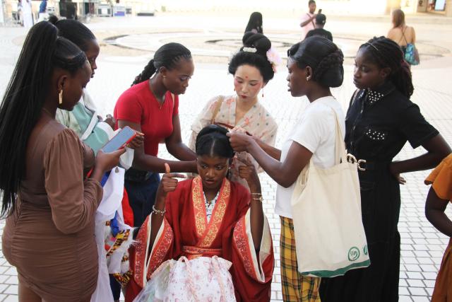 (251109) -- COTONOU, Nov. 9, 2025 (Xinhua) -- Students from the Confucius Institute of the University of Abomey-Calavi prepare their traditional Chinese attires for the China-Benin Fashion Show at the central square of the Palais des Congres in Cotonou, Benin, Nov. 8, 2025. TO GO WITH "Feature: China-Benin Fashion Show weaves friendship through silk and cotton" (Photo by Seraphin Zounyekpe/Xinhua)