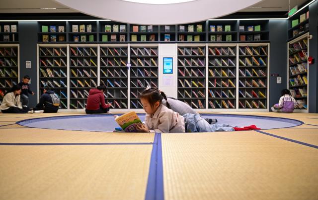 (251109) -- SHANGHAI, Nov. 9, 2025 (Xinhua) -- Children read books at a public library in east China's Shanghai, Nov. 9, 2025. In recent years, Shanghai has focused on optimizing historical and cultural districts, developing urban cultural lifestyle areas, enriching citizens' cultural lives, and promoting the deep integration of culture and tourism. (Xinhua/Cai Xiangxin)