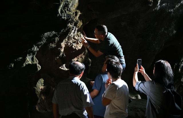 (251110) -- SANYA, Nov. 10, 2025 (Xinhua) -- Archaeologists observe the excavation site of the Luobi Cave relic site in Sanya, south China's Hainan Province, Nov. 8, 2025. A prehistoric tomb dating back between 12,000 and 13,000 years was discovered in south China's Hainan Province, which is believed to be the earliest tomb found on the island.
   The tomb, discovered at the Luobi Cave relic site in Sanya's Jiyang District, belonged to a child who was buried on his or her side with bent limbs. Shell ornaments were found near the head and waist, believed to be the earliest of their kind in China, offering valuable insights into Hainan's prehistoric culture and its cultural exchanges with Southeast Asia. (Xinhua/Guo Cheng)