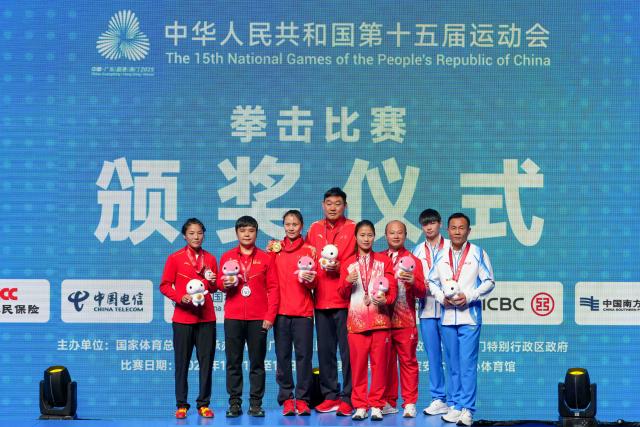 (251110) -- SHENZHEN, Nov. 10, 2025 (Xinhua) -- Gold medalist Xu Zichun of Jiangsu, silver medalist Cai Yan of Hebei, bronze medalists Ren Meijuan of Jilin, Ge Yaqi of Zhejiang and their coaches pose for group photos during the awarding ceremony for the women's -57kg of boxing at China's 15th National Games in Shenzhen, south China's Guangdong Province, Nov. 10, 2025. (Xinhua/Peng Yikai)