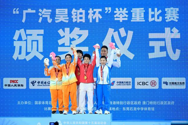 (251110) -- DONGGUAN, Nov. 10, 2025 (Xinhua) -- Gold medalist Hou Zhihui of Hunan, silver medalist Deng Xiaofang of Hainan, bronze medalist Yu Mengqian of Zhejiang and their coaches pose during the awarding ceremony for the weightlifting women's 49kg at China's 15th National Games in Dongguan, south China's Guangdong Province, Nov. 10, 2025. (Xinhua/Yang Chenguang)