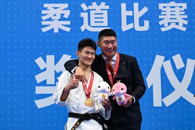 (251110) -- ZHAOQING, Nov. 10, 2025 (Xinhua) -- Gold medalist Ma Yulin (L) of Shandong poses for photos with his coach during the awarding ceremony of the men's Judo -60kg at China's 15th National Games in Zhaoqing, south China's Guangdong Province, Nov. 10, 2025. (Xinhua/Zhu Xiang)
