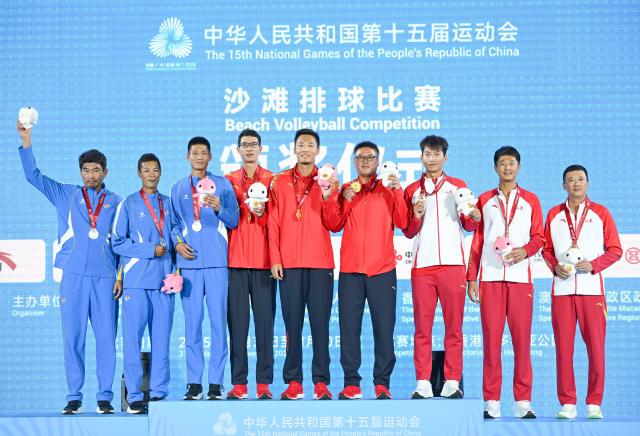 (251110) -- HONG KONG, Nov. 10, 2025 (Xinhua) -- Gold medalists Wu Jiaxin/Zhou Chaowei of Jiangsu, silver medalists Li Zhuoxin/Xue Tao of Liaoning and bronze medalists Wang Yanwei/Du Hongjun of Shandong pose with their coaches during the awarding ceremony for the men's beach volleyball at China's 15th National Games in Hong Kong, south China, Nov. 10, 2025. (Xinhua/Hu Huhu)
