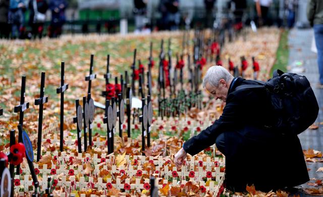 (251110) -- LONDON, Nov. 10, 2025 (Xinhua) -- A man arranges poppy petals and crosses at the Field of Remembrance on the occasion of Remembrance Day at Westminster Abbey in London, Britain, Nov. 10, 2025. Remembrance Day is observed to remember the sacrifices made by soldiers during the WWI, which ended on Nov. 11, 1918. (Xinhua/Li Ying)