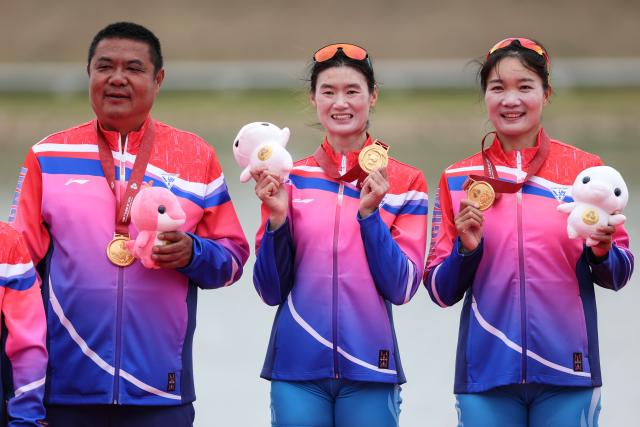 (251111) -- GUANGZHOU, Nov. 11, 2025 (Xinhua) -- Gold medalists Chen Yunxia (C)/Zhang Ling (R) of Shanghai pose with their coach during the awarding ceremony after the women's double sculls final of rowing at China's 15th National Games in Guangzhou, south China's Guangdong Province, Nov. 11, 2025. (Xinhua/Pan Yulong)