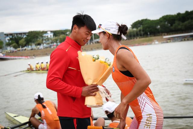 (251110) -- GUANGZHOU, Nov. 10, 2025 (Xinhua) -- Han Wei (L) of Hebei gives a bouquet of flowers to his girlfriend, Wu Yongmei of Hubei, after the women's four final of rowing at China's 15th National Games in Guangzhou, south China's Guangdong Province, Nov. 11, 2025. (Xinhua/Pan Yulong)