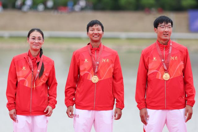 (251111) -- GUANGZHOU, Nov. 11, 2025 (Xinhua) -- Gold medalists Cui Binghui (R)/Bian Shihao (C) of Henan pose with their coach during the awarding ceremony for the men's pair of rowing at China's 15th National Games in Guangzhou, south China's Guangdong Province, Nov. 11, 2025. (Xinhua/Pan Yulong)