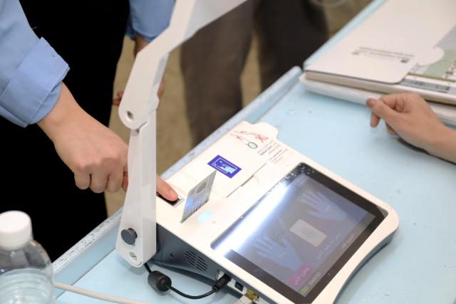 (251111) -- BAGHDAD, Nov. 11, 2025 (Xinhua) -- A man has his fingerprint scanned before casting his vote at a polling station in Baghdad, Iraq, on Nov. 11, 2025. Iraqis began to vote in parliamentary elections on Tuesday morning for a new 329-member Council of Representatives. (Xinhua/Khalil Dawood)