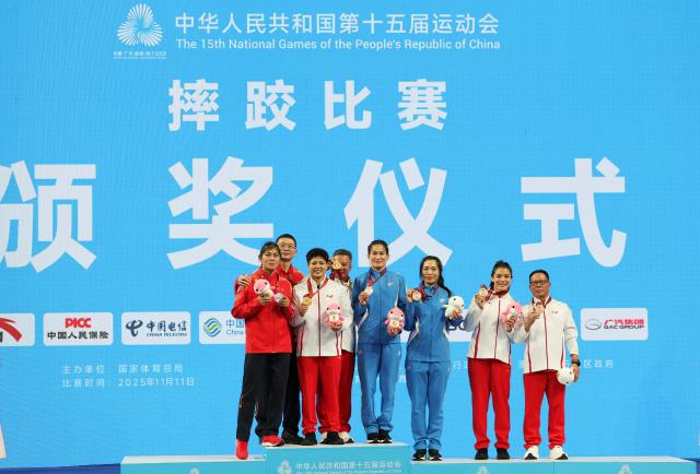 (251111) -- QINGYUAN, Nov. 11, 2025 (Xinhua) -- Gold medalist Long Jia of Yunnan, silver medalist Han Yue of Jiangsu, bronze medalist Zhou Feng of Liaoning and bronze medalist Li Zelu of Yunnan pose with their coaches during the awarding ceremony after the women's freestyle 68kg of wrestling at China's 15th National Games in Qingyuan, south China's Guangdong Province, Nov. 11, 2025. (Xinhua/Li Ran)