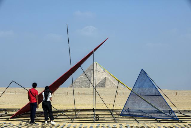 (251111) -- CAIRO, Nov. 11, 2025 (Xinhua) -- Visitors view an artwork exhibited during the "Forever Is Now" international art exhibition at Giza Pyramids scenic spot in Giza, Egypt, Nov. 11, 2025. The fifth edition of "Forever Is Now" international art exhibition on Tuesday kicked off in the area of Egypt's Giza Pyramids scenic spot, showcasing 10 artworks of artists from different countries. The exhibition runs from Nov. 11 to Dec. 6. (Xinhua/Ahmed Gomaa)