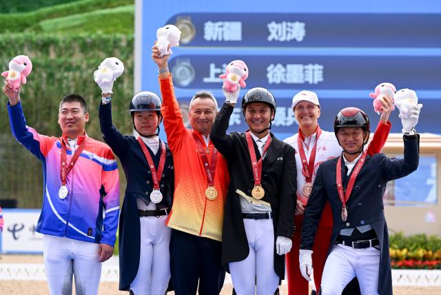 (251112) -- SHENZHEN, Nov. 12, 2025 (Xinhua) -- Gold medalist Liu Tao (3nd R) of Xinjiang, silver medalist Xu Mofei (2nd L) of Shanghai and bronze medalist Gu Bing (1st R) of Guangdong pose with their coaches during the awarding ceremony for the equestrian dressage individual final at China's 15th National Games in Shenzhen, south China's Guangdong Province, Nov. 12, 2025. (Xinhua/Feng Kaihua)