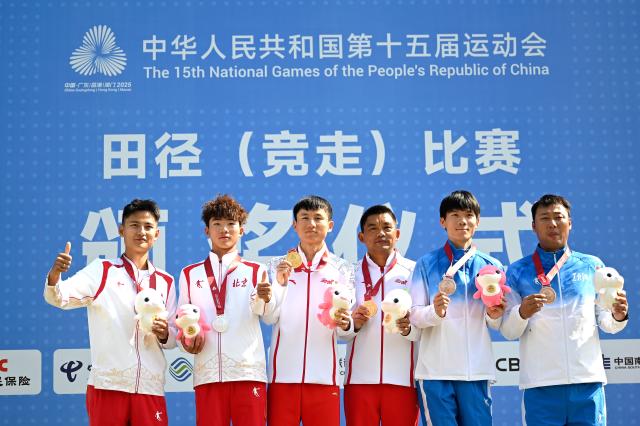 (251112) -- ZHUHAI, Nov. 12, 2025 (Xinhua) -- Gold medalist Zhang Jun (3rd L) of Yunnan, silver medalist Shi Shengji (2nd L) of Beijing and bronze medalist Qian Haifeng (2nd R) of Heilongjiang pose with their coaches during the awarding ceremony for the men's 20km race walk of athletics at China's 15th National Games in Zhuhai, south China's Guangdong Province, Nov. 12, 2025. (Xinhua/Zhang Long)