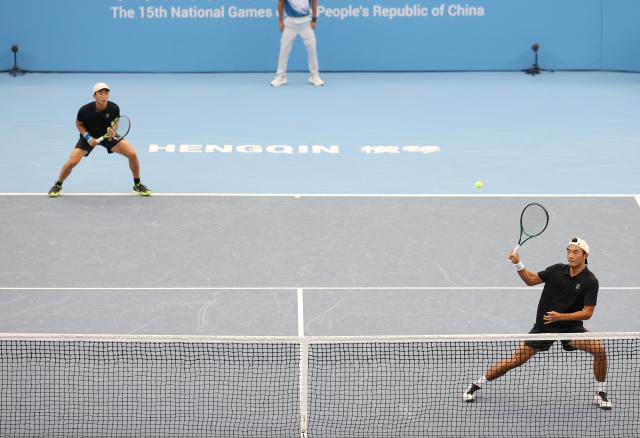 (251112) -- HENGQIN, Nov. 12, 2025 (Xinhua) -- Chen Xianfeng/Xu Kuangqing (R) of Jiangsu compete in the men's doubles match against Song Yuqiao/Zhang Boxiong of Beijing during the junior men's team final of tennis between Beijing and Jiangsu at China's 15th National Games in Hengqin, south China's Guangdong Province, Nov. 12, 2025. (Xinhua/Zhang Chenlin)