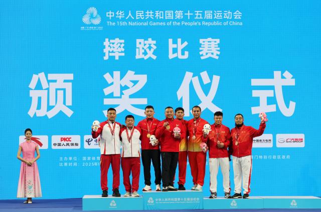 (251112) -- QINGYUAN, Nov. 12, 2025 (Xinhua) -- Gold medalist Li Peilong of Hebei, silver medalist Bi Shengfeng of Shangdong, bronze medalist Zhang Heng of Henan and bronze medalist Ayidusi Hade of Xinjiang pose with their coaches during the awarding ceremony after the men's freestyle 86kg final of wrestling at China's 15th National Games in Qingyuan, south China's Guangdong Province, Nov. 12, 2025. (Xinhua/Li Ran)