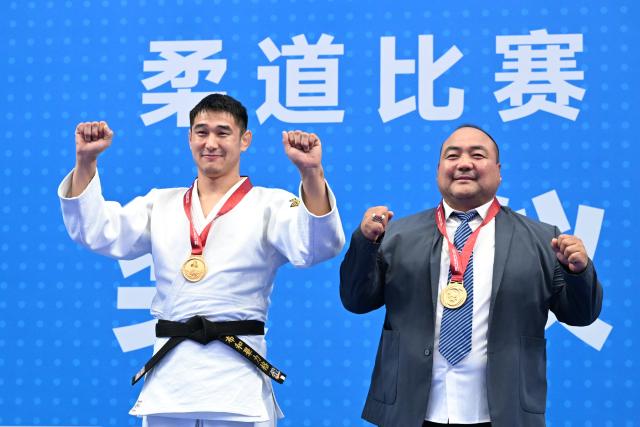 (251112) -- ZHAOQING, Nov. 12, 2025 (Xinhua) -- Gold medalist Buhebilige of Inner Mongolia poses with his coach during the awarding ceremony for Judo men's -90kg at China's 15th National Games in Zhaoqing, south China's Guangdong Province, Nov. 12, 2025. (Xinhua/Zhu Xiang)