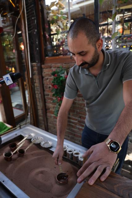 (251113) -- ANKARA, Nov. 13, 2025 (Xinhua) -- A barista brews coffee with hot sand in Ankara, Türkiye, Nov. 12, 2025. The brewing process of Turkish sand coffee involves little coffee pots nestling in a bed of hot sand. (Mustafa Kaya/Handout via Xinhua)