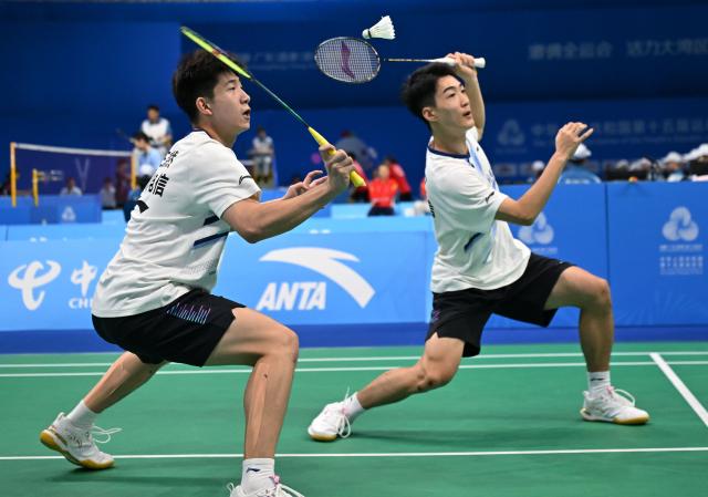 (251113) -- SHENZHEN, Nov. 13, 2025 (Xinhua) -- Zhou Chuanyou/Wang Xinran (L) of Sichuan compete against Wang Xiaokai/Xiao Songyuan of Beijing during the U18 men's team bronze medal match of badminton between Beijing and Sichuan at China's 15th National Games in Shenzhen, south China's Guangdong Province, Nov. 13, 2025. (Xinhua/Li Ziheng)