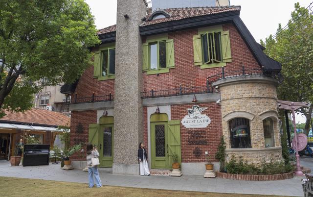 (251113) -- SHANGHAI, Nov. 13, 2025 (Xinhua) -- A visitor poses for photos at the Yuyuan Road Historical and Cultural Block in east China's Shanghai, Nov. 12, 2025.
  The Yuyuan Road Historical and Cultural Block is a well-known neighborhood in the city's downtown area. In recent years, the block has consistently pursued an urban renewal philosophy that integrates art into daily life. By introducing independent bookstores, cafes, art studios, and other establishments, it now boasts around 80 distinctive shops, making it a must-visit destination for Shanghai's artistic youth and travelers. (Xinhua/Cai Yang)