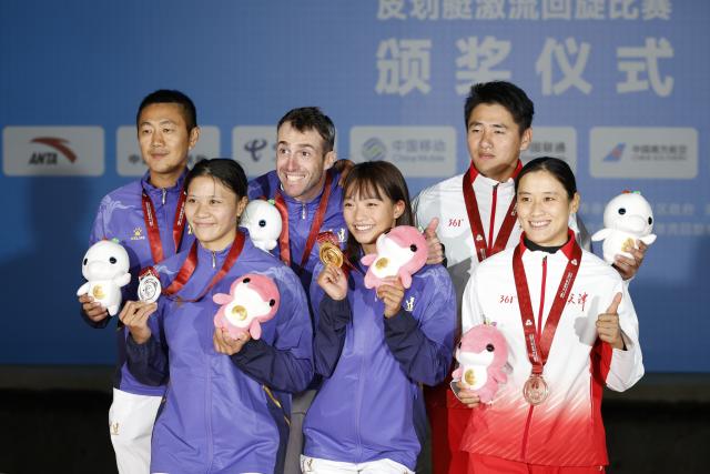 (251113) -- GUANGZHOU, Nov. 13, 2025 (Xinhua) -- Gold medalist Li Shiting of Fujian, silver medalist Xie Xueting of Fujian and bronze medalist Chen Lin of Tianjin pose with their coaches during the awarding ceremony for the women's kayak single of canoe slalom at China's 15th National Games in Guangzhou, south China's Guangdong Province, Nov. 13, 2025. (Xinhua/Huang Wei)
