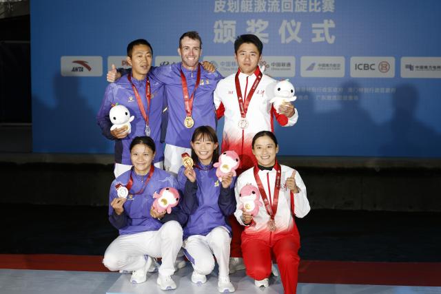 (251113) -- GUANGZHOU, Nov. 13, 2025 (Xinhua) -- Gold medalist Li Shiting of Fujian, silver medalist Xie Xueting of Fujian and bronze medalist Chen Lin of Tianjin pose with their coaches during the awarding ceremony for the women's kayak single of canoe slalom at China's 15th National Games in Guangzhou, south China's Guangdong Province, Nov. 13, 2025. (Xinhua/Huang Wei)