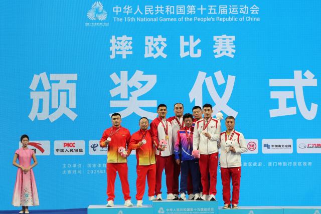 (251113) -- QINGYUAN, Nov. 13, 2025 (Xinhua) -- Gold medalist Liu Rui of Shandong, silver medalist Bahejiang Halishan of Xinjiang, bronze medalist Wang Zhihuan of Shanghai and bronze medalist Pan Chunyang of Beijing pose with their coaches during the awarding ceremony after the men's Greco Roman 77kg final of wrestling at China's 15th National Games in Qingyuan, south China's Guangdong Province, Nov. 13, 2025. (Xinhua/Li Ran)