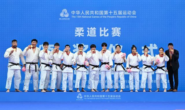 (251113) -- ZHAOQING, Nov. 13, 2025 (Xinhua) -- Gold medalists team Shandong pose with their coach during the awarding ceremony for Judo mixed team between Shandong and Inner Mongolia at China's 15th National Games in Zhaoqing, south China's Guangdong Province, Nov. 13, 2025. (Xinhua/Zhu Xiang)