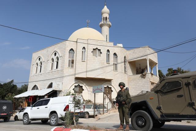 (251113) -- RAMALLAH, Nov. 13, 2025 (Xinhua) -- A member of Israeli forces guards the "Hajjah Hamidah" mosque in the town of Deir Istiya, northwest of Salfit in the West Bank, Nov. 13, 2025. Israeli settlers set fire to parts of a mosque northwest of Salfit in the West Bank on Thursday and wrote anti-Islam slogans on its walls, the Palestinian Liberation Organization's Commission Against the Wall and Settlements said in a brief statement. (Photo by Nidal Eshtayeh/Xinhua)