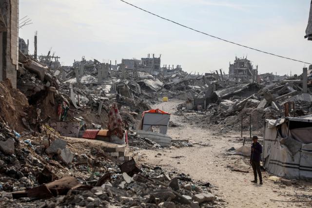 (251113) -- GAZA, Nov. 13, 2025 (Xinhua) -- A Palestinian is seen in a street with destroyed homes in Jabalia city, northern Gaza Strip, with yellow-painted concrete blocks placed by the Israeli army visible in the background that marks the Yellow Line, Nov. 2, 2025. TO GO WITH Feature: Gaza's new divide -- "Yellow Line" shapes life under fragile ceasefire (Photo by Rizek Abdeljawad/Xinhua)