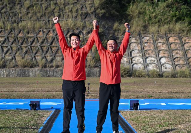 (251114) -- GUANGZHOU, Nov. 14, 2025 (Xinhua) -- Gold medalist Zhang Yukun (L) of Jiangsu celebrates during the awarding ceremony for the skeet men's of shooting at China's 15th National Games in Guangzhou, south China's Guangdong Province, Nov. 14, 2025. (Xinhua/Xiao Ennan)