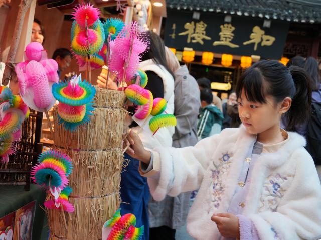 (251114) -- SHANGHAI, Nov. 14, 2025 (Xinhua) -- A girl visits a fair of intangible cultural heritage products in Yuyuan Garden, Shanghai, east China, Nov. 14, 2025. A series of cultural events were held here to showcase the charm of Chinese intangible cultural heritages. 
   Located near the Bund in central Shanghai, Yuyuan Garden is a landmark attraction in this east China metropolis. Last year, it welcomed a record 2.7 million visitors -- with international tourists comprising nearly one-fourth of that total. (Xinhua/Liu Ying)