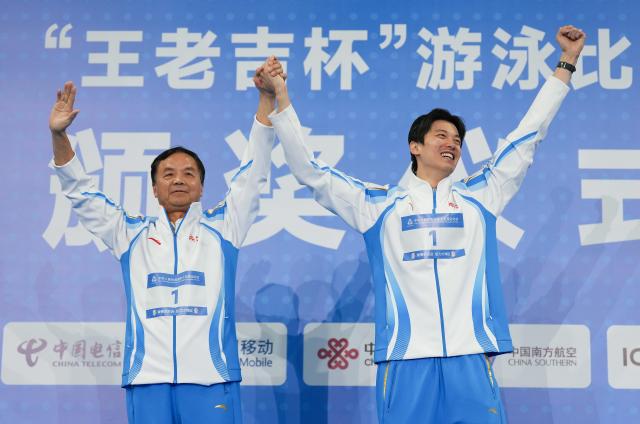 (251114) -- SHENZHEN, Nov. 14, 2025 (Xinhua) -- Gold medalist Wang Shun of Zhejiang and his coach wave during the awarding ceremony for the men's 200m individual medley of swimming at China's 15th National Games in Shenzhen, south China's Guangdong Province, Nov. 14, 2025. (Xinhua/Xue Yuge)