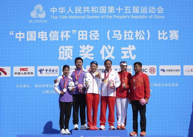 (251115) -- SHENZHEN, Nov. 15, 2025 (Xinhua) -- Gold medalist Zhang Deshun (3rd L) of Yunnan, silver medalist Individual Athlete Ciren Cuomu (1st L), bronze medalist Lu Ying (2nd R) of Henan pose with their coaches during the awarding ceremony for the women's marathon event at China's 15th National Games in Shenzhen, south China's Guangdong Province, Nov. 15, 2025. (Xinhua/Jiang Han)