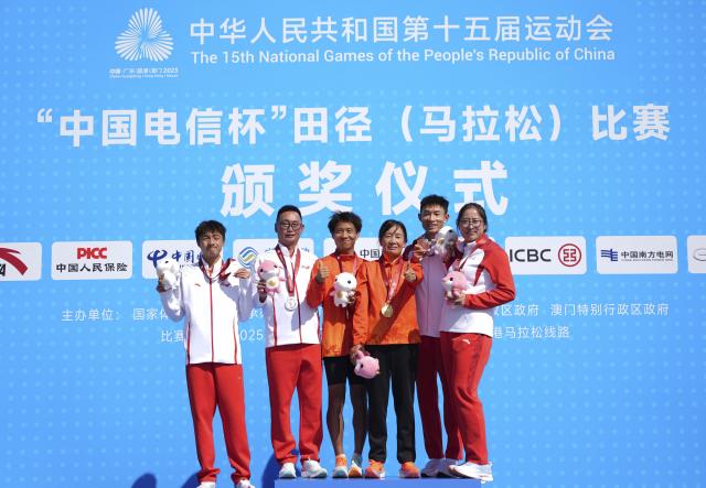 (251115) -- SHENZHEN, Nov. 15, 2025 (Xinhua) -- Gold medalist He Jie of Ningxia (3rd L), silver medalist Gao Peng (1st L) of Yunnan and bronze medalist Wu Xiangdong (2nd R) of Anhui pose with their coaches during the awarding ceremony for the men's marathon event at China's 15th National Games in Shenzhen, south China's Guangdong Province, Nov. 15, 2025. (Xinhua/Jiang Han)