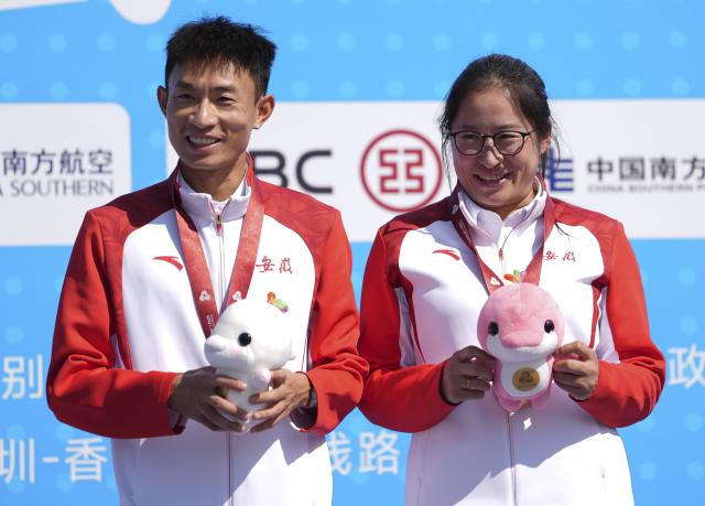 (251115) -- SHENZHEN, Nov. 15, 2025 (Xinhua) -- Bronze medalist Wu Xiangdong (L) of Anhui reacts during the awarding ceremony for the men's marathon event at China's 15th National Games in Shenzhen, south China's Guangdong Province, Nov. 15, 2025. (Xinhua/Jiang Han)