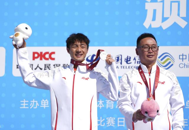 (251115) -- SHENZHEN, Nov. 15, 2025 (Xinhua) -- Silver medalist Gao Peng (L) of Yunnan reacts during the awarding ceremony for the men's marathon event at China's 15th National Games in Shenzhen, south China's Guangdong Province, Nov. 15, 2025. (Xinhua/Jiang Han)